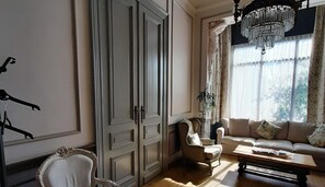 Une pièce comprenant une grande armoire, un canapé, un fauteuil et un lustre.