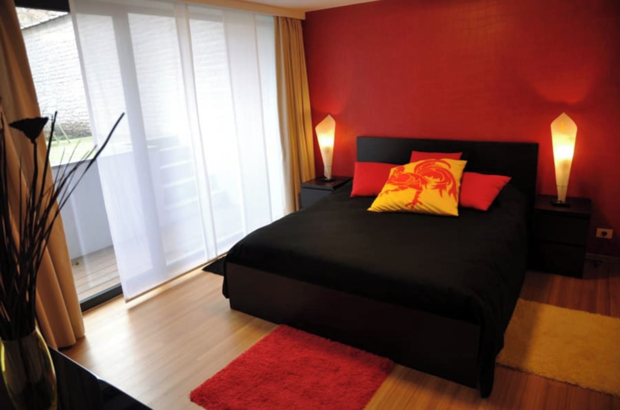 Une chambre à coucher moderne avec un lit noir, des oreillers rouges et deux lampes de chevet.