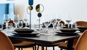 A dining table set with plates, bowls, and glasses, with chairs around it.