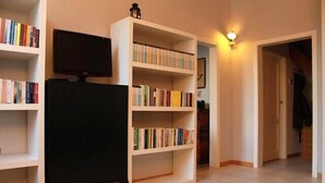 A room with a bookshelf, a flat-screen TV, and a light fixture. - Stylish & Comfortable Apartment in Vibrant Neighborhood –Perfect for Short Stays (Firenze)