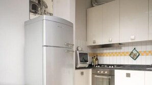 A compact kitchen with a built-in oven, a microwave, and a refrigerator. - Stylish & Comfortable Apartment in Vibrant Neighborhood –Perfect for Short Stays (Firenze)