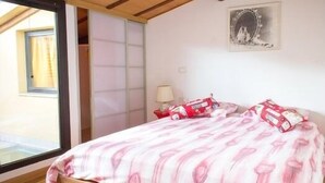 A bedroom with a wooden bed, a window, a wall-mounted lamp, and a framed picture. - Stylish & Comfortable Apartment in Vibrant Neighborhood –Perfect for Short Stays (Firenze)