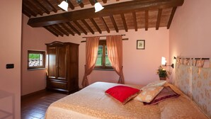 Un dormitorio con cama, ventana, cortinas, armario de madera y una planta en maceta.