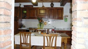 Una cocina con armarios de madera, salpicadero de azulejos y un comedor con mesa y sillas.