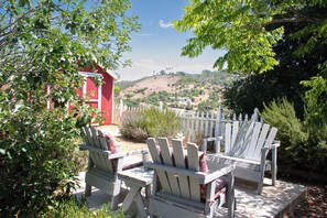 A patio with Adirondack chairs and a red building in the background. - Farm Stay Bungalow And Hot Tub (Rainbow)