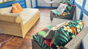 Une pièce avec un canapé en osier, un fauteuil rembourré et un hamac.