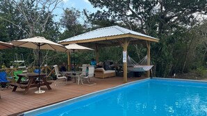 Une piscine entourée d’une terrasse en bois, de chaises longues et de parasols.