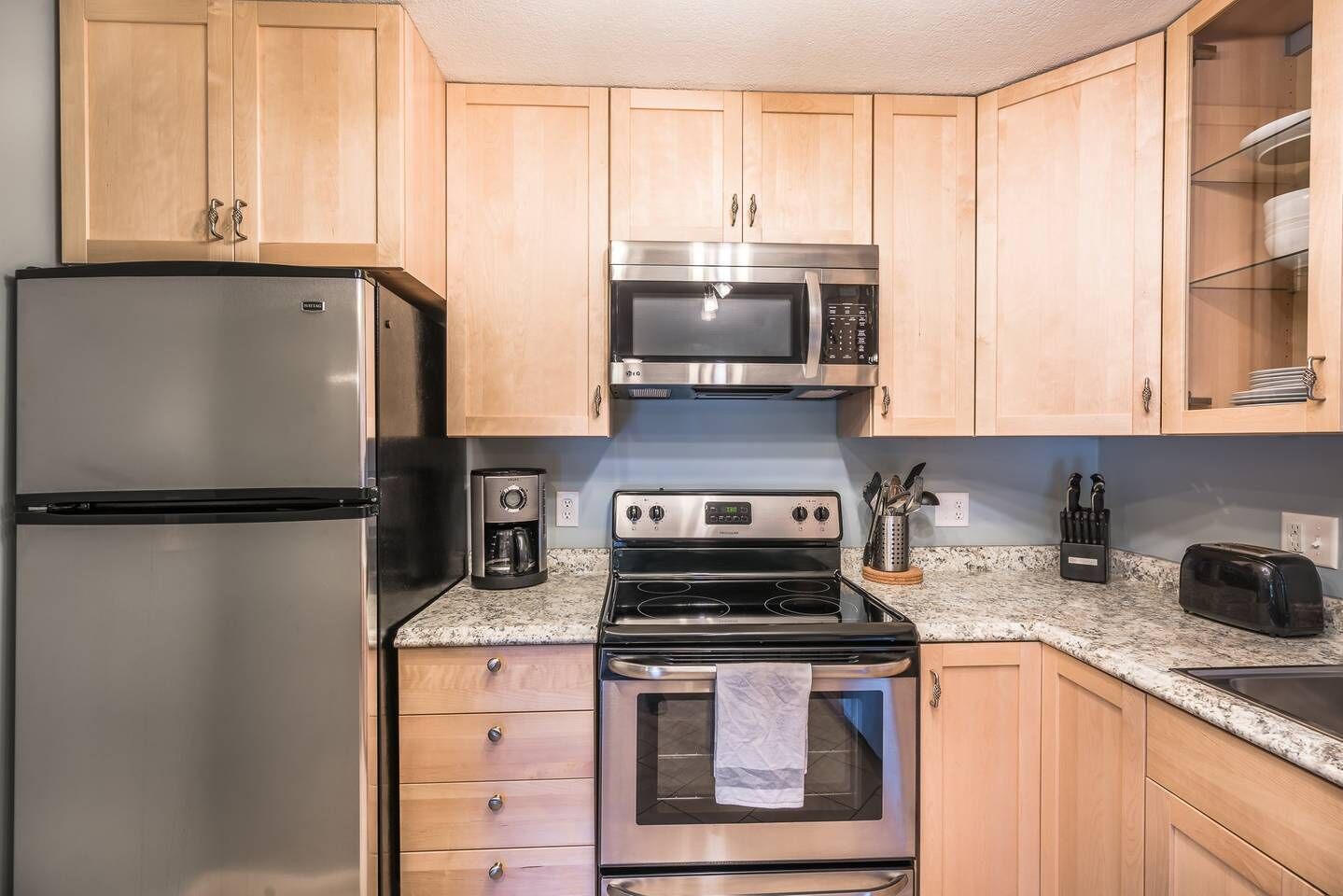 A kitchen with a stainless steel refrigerator, a microwave, a stove, and a toaster.