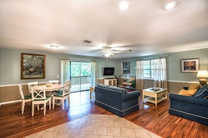 Relax in this inviting living area with a dining table, sofa, and TV, surrounded by windows and a fireplace.
