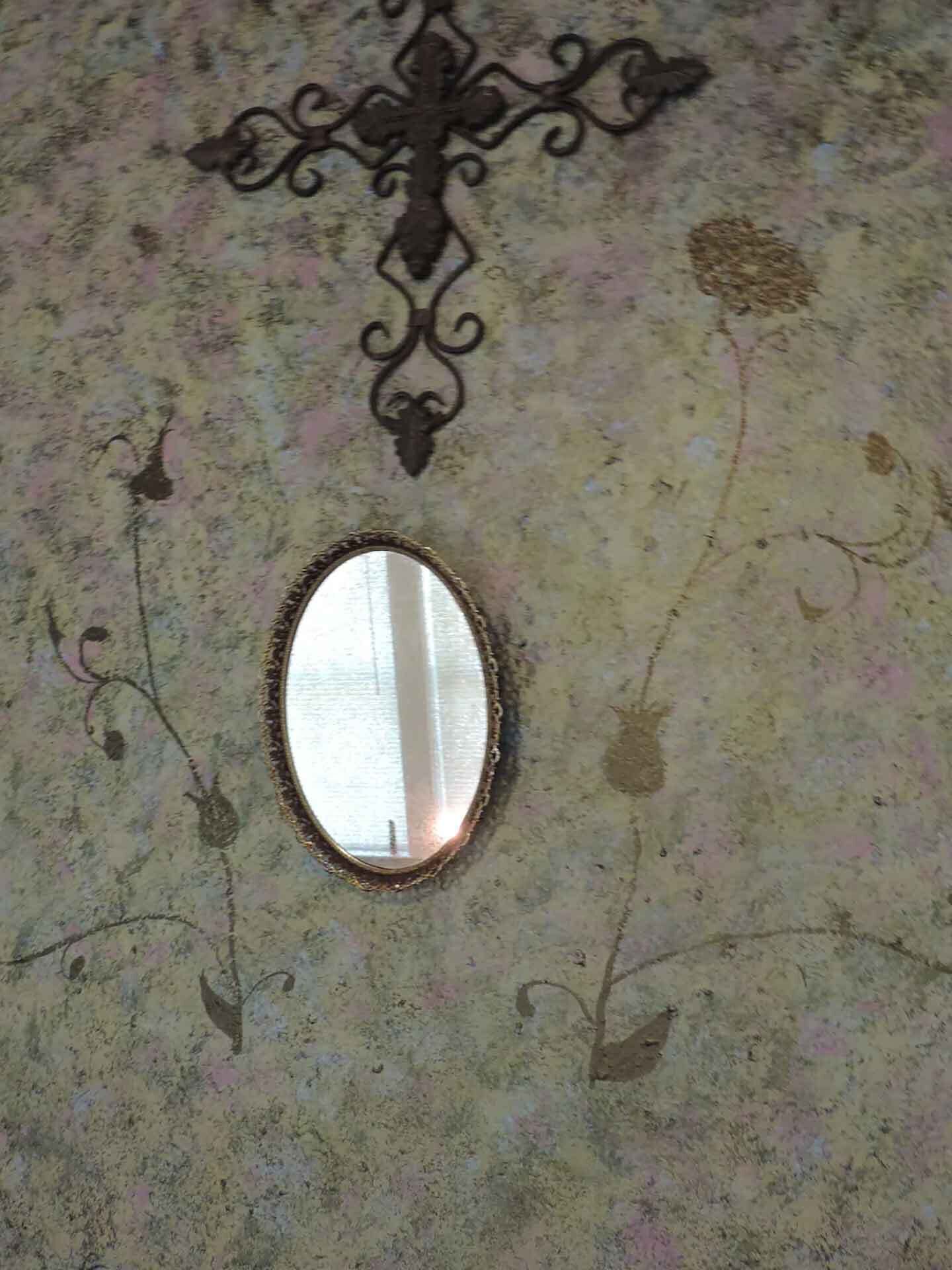 A mirror with a decorative frame on a textured wall.