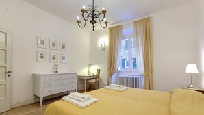 A bedroom with a bed, a desk, a chair, a dresser, and a window with curtains. - Bardi Apartment, Stunning View Of Ponte Vecchio! (Florence)
