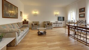 A living room with a sofa, armchairs, a coffee table, and a TV. - Bardi Apartment, Stunning View Of Ponte Vecchio! (Florence)