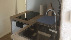 Een praktische keuken met een spoelbak, een kookplaat en een klein aanrecht.