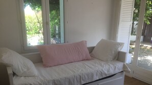 Een witte ligbank met twee kussens, een raam en een houten vloer.