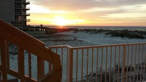 A beach view with a wooden railing and a building in the background. - Harbor House-Unit B21-Beachfront Paradise in the Heart of Gulf Shores (Gulf Shores)