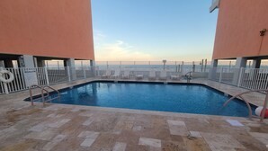 A swimming pool with a tiled deck, surrounded by a white fence, and a 'Pool Rules' sign. - Harbor House-Unit B21-Beachfront Paradise in the Heart of Gulf Shores (Gulf Shores)