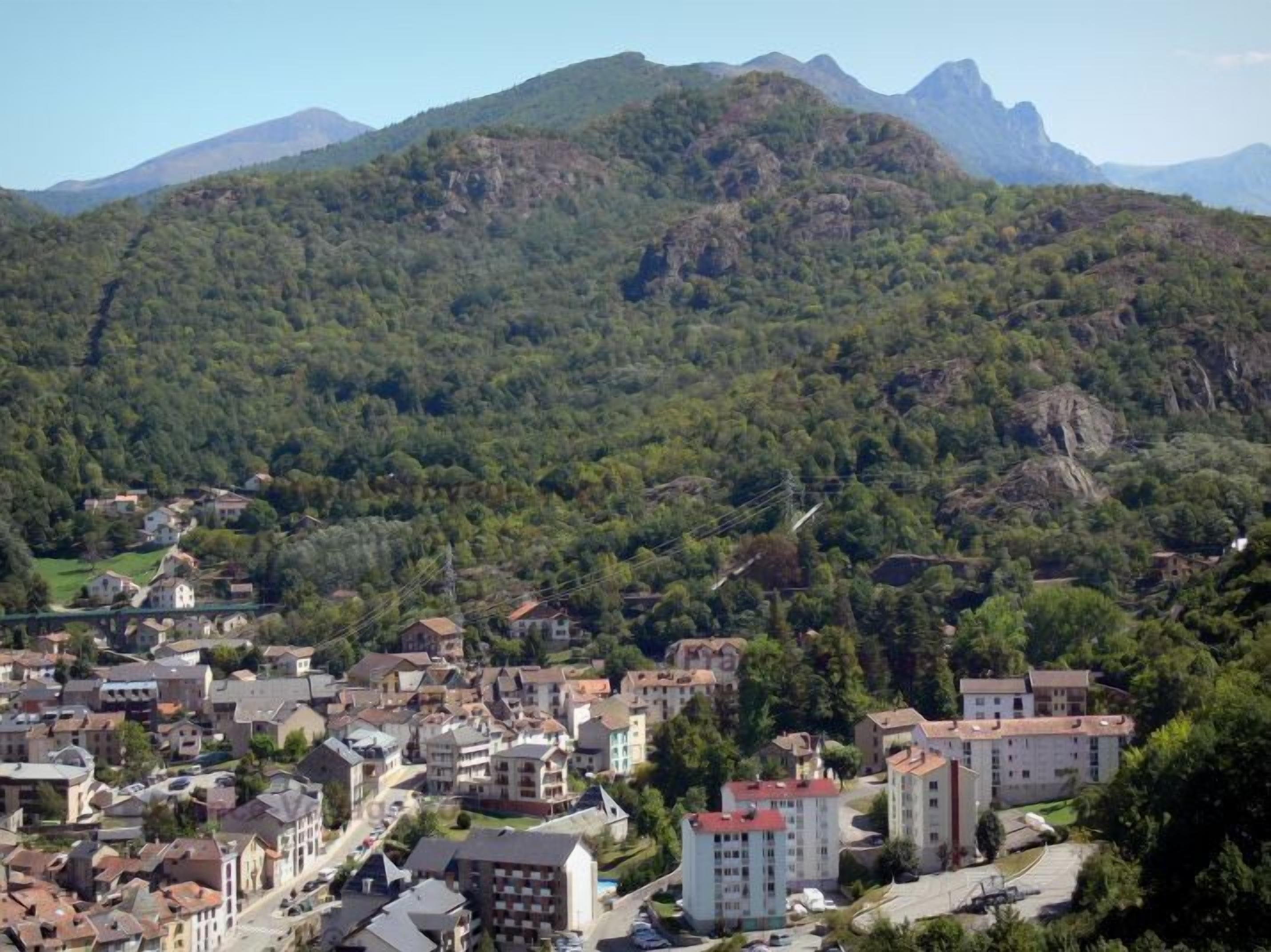 Eine Stadt eingebettet in ein Tal, mit Bergel in der Ferne.