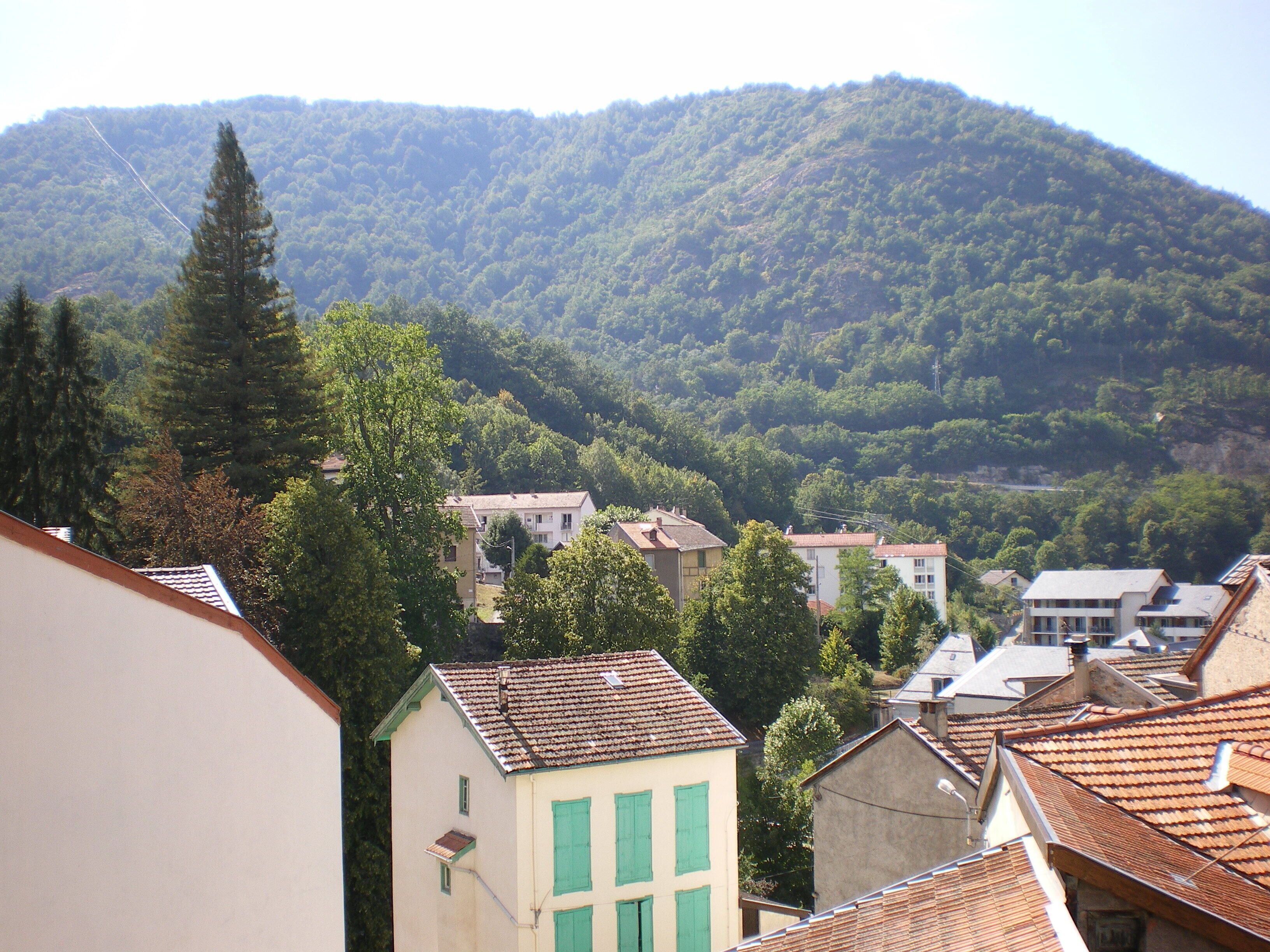 A hillside village with traditional buildings, a prominent church, and a mountain backdrop.