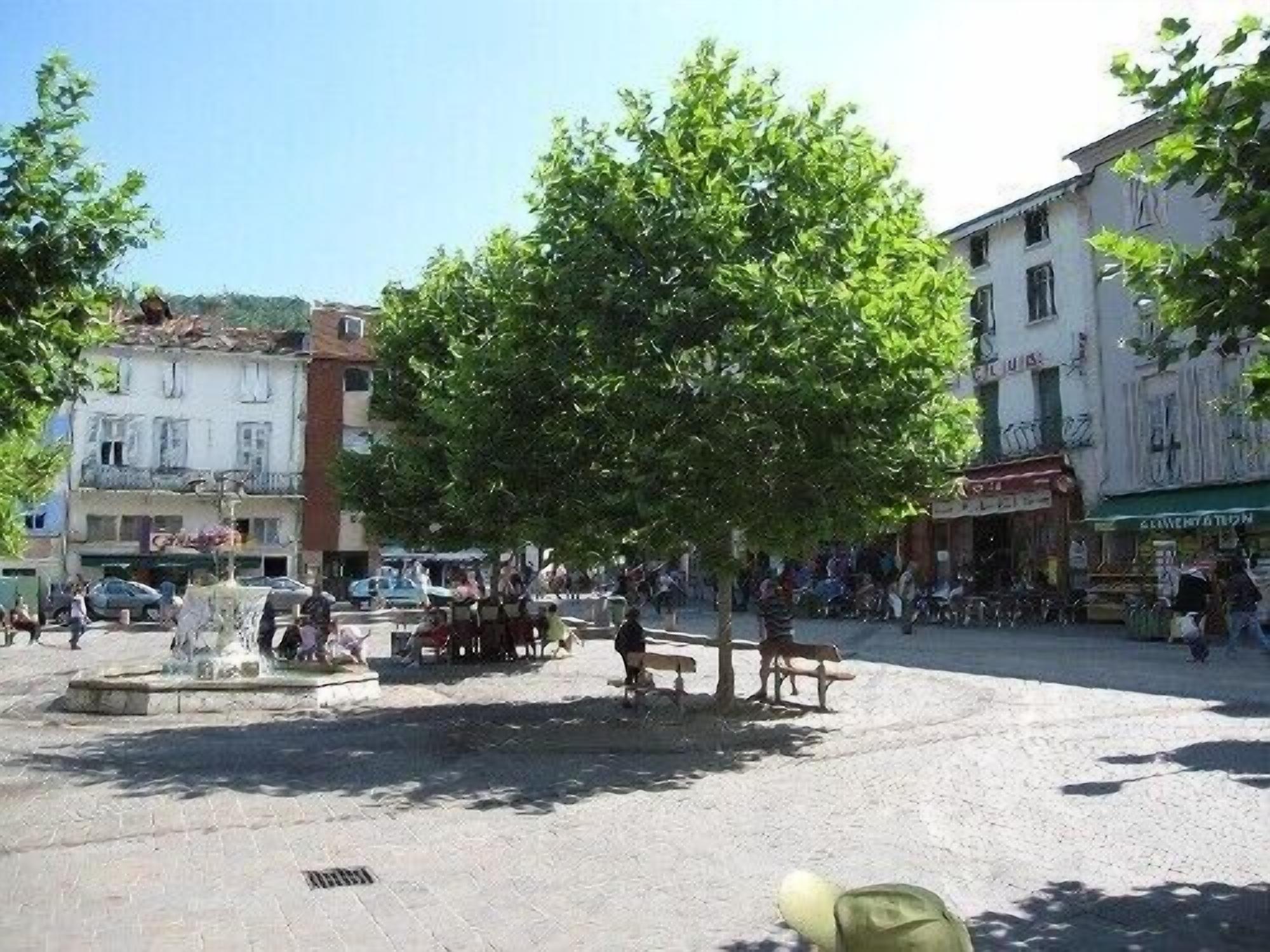 Une place publique avec une fontaine, des bancs et des passants.