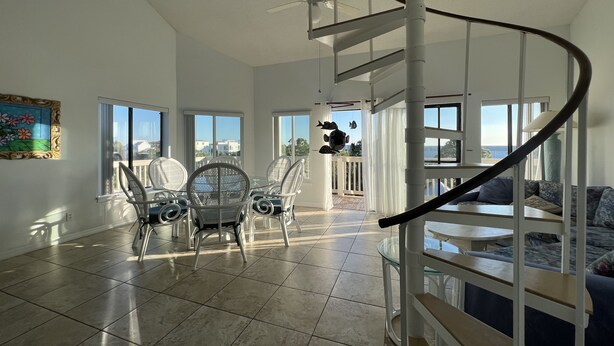 A spacious living area with a spiral staircase, large windows, and a dining set. - Walk to the beach! 2 bedroom 2 bath condo with a loft.  (Santa Rosa Beach)