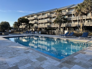 Relax by the pool surrounded by lush greenery and comfortable lounge chairs.