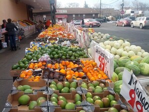 Un puesto de frutas y verduras con sandías, mangos y naranjas, a 99 centavos el peso.