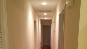 Un couloir étroit avec un plancher en bois et des murs blancs.