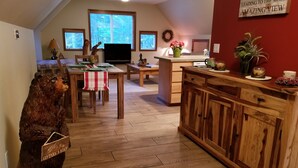A cozy kitchen with wooden cabinets, a dining table, and a bear statue. - Cozy Studio Apartment Near Crystal Mtn Ski Resort & Mt Rainier National Park (Enumclaw)