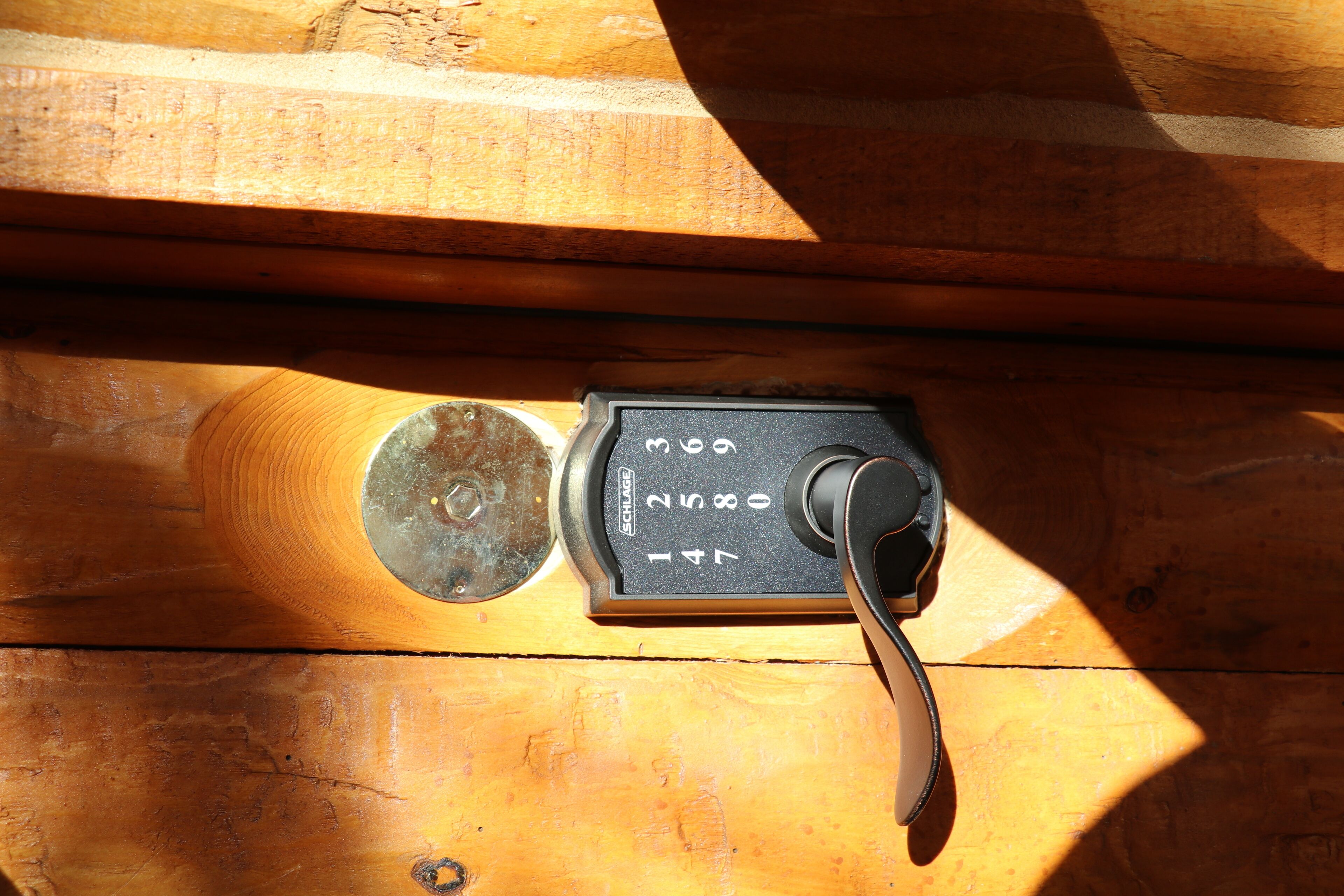 A wooden surface with a metal object that appears to be a lock or a combination device.
