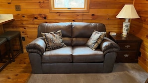 A brown leather sofa with two patterned cushions, a wooden wall, a window, and a lamp on a wooden nightstand. - Cabin on 4 acres/very private/Dogs OK/Easy Drive from Philly and NYC (Jackson)