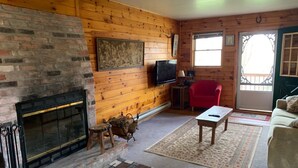 A cozy living room with a fireplace, a television, a red chair, a coffee table, and a patterned rug. - Cabin on 4 acres/very private/Dogs OK/Easy Drive from Philly and NYC (Jackson)
