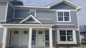 Une maison à deux étages avec un garage, des portes numérotées et un porche abrité.