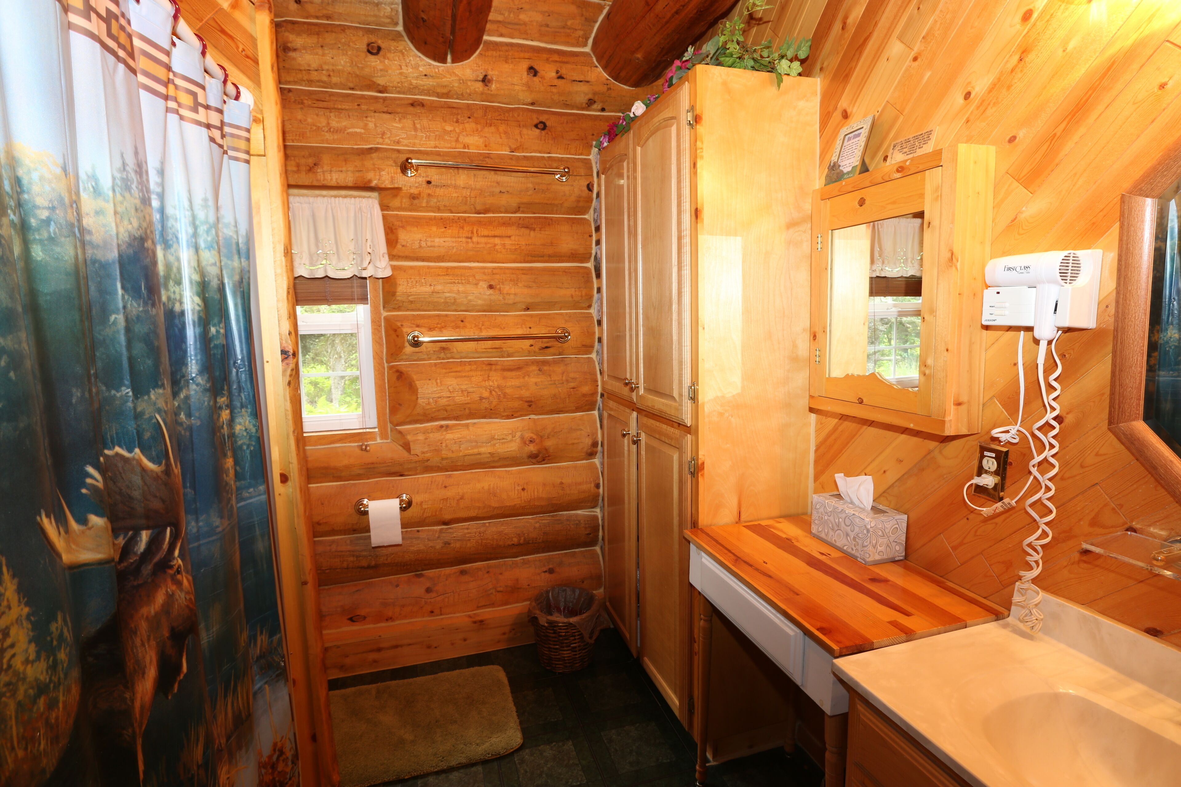 A wooden cabin bathroom with a wooden sink, a hairdryer, and a mirror.
