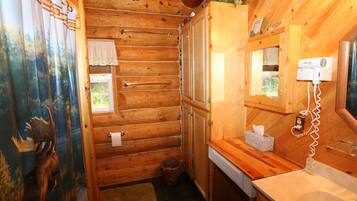 A wooden cabin bathroom with a wooden sink, a hairdryer, and a mirror.