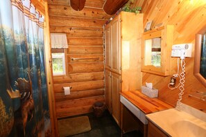 A wooden cabin bathroom with a shower, a towel rack, a mirror, and a hairdryer. - Hunter - Unique Alaskan log home in trees & wildflowers on 14-acre homestead. (Anchor Point)