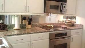 A kitchen with white cabinets, a microwave, and a stainless steel oven. - Fabulous Turtle Creek Location! (Dallas)