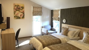 Habitación de hotel con dos camas, un escritorio, una silla y un televisor.
