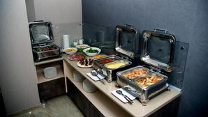 Un montaje tipo bufé con diversos alimentos en recipientes metálicos, platos y tazones.