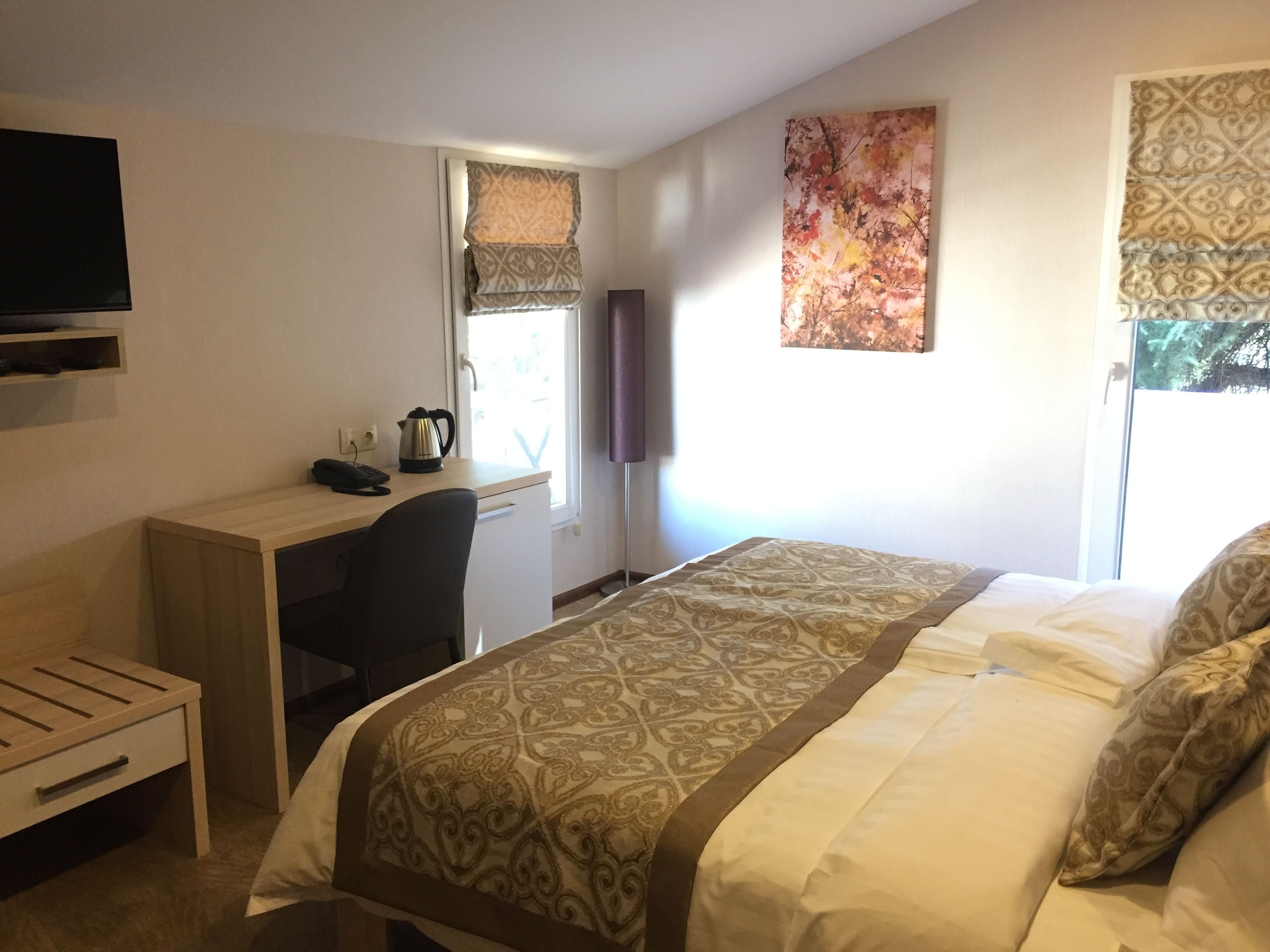 Ein Hotelzimmer mit einem Bett, einem Schreibtisch, einem Sessel, einem Fernseher und einem Fenster mit Vorhängen.