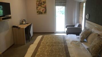 A bedroom with a bed, a desk, a chair, and a television.