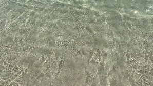Helder ondiep water met een verre horizon en enkele boten.