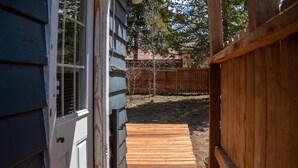 Eine Holzterrasse führt zu einem Haus mit einem eingezäunten Garten.