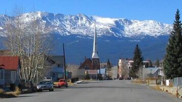 Une rue bordée d’immeubles et d’une église, avec des montagnes enneigées en arrière-plan.