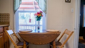 Ein Holzespeisetisch mit zwei Stühlen, einer Blumenvase und einem Fenster mit Jalousien.