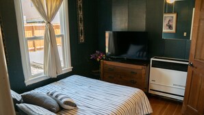 Ein Schlafzimmer mit Bett, Fernseher, Kommode und Heizung.