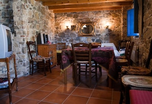 Enjoy meals in this charming dining area with a stone wall, wooden beams, and a dining table set with chairs.