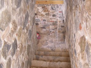 Staircase with rough-hewn walls and uneven steps, showcasing the property's historic charm.