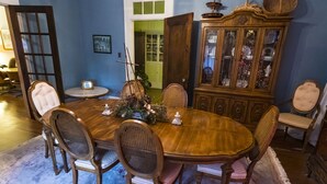 Ein Esszimmer mit Holztisch, umgeben von sechs Stühlen, einem Schrank mit Glastüren und einer Tür zu einem anderen Raum.