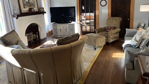 Ein Wohnzimmer mit Kamin, Fernseher und einer Chandelüster.