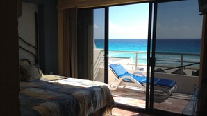 Ein Schlafzimmer mit Bett, Deckenventilator und Meerblick durch eine Schiebetür.